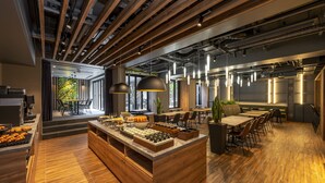 Un restaurante moderno con barra de madera, asientos y vistas a zonas verdes exteriores.