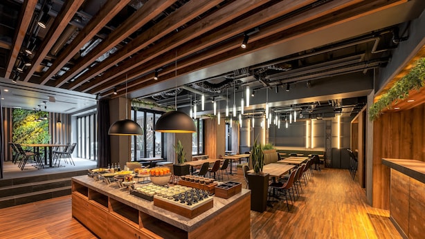 Un restaurante moderno con barra de madera, iluminación colgante y vistas a zonas verdes.