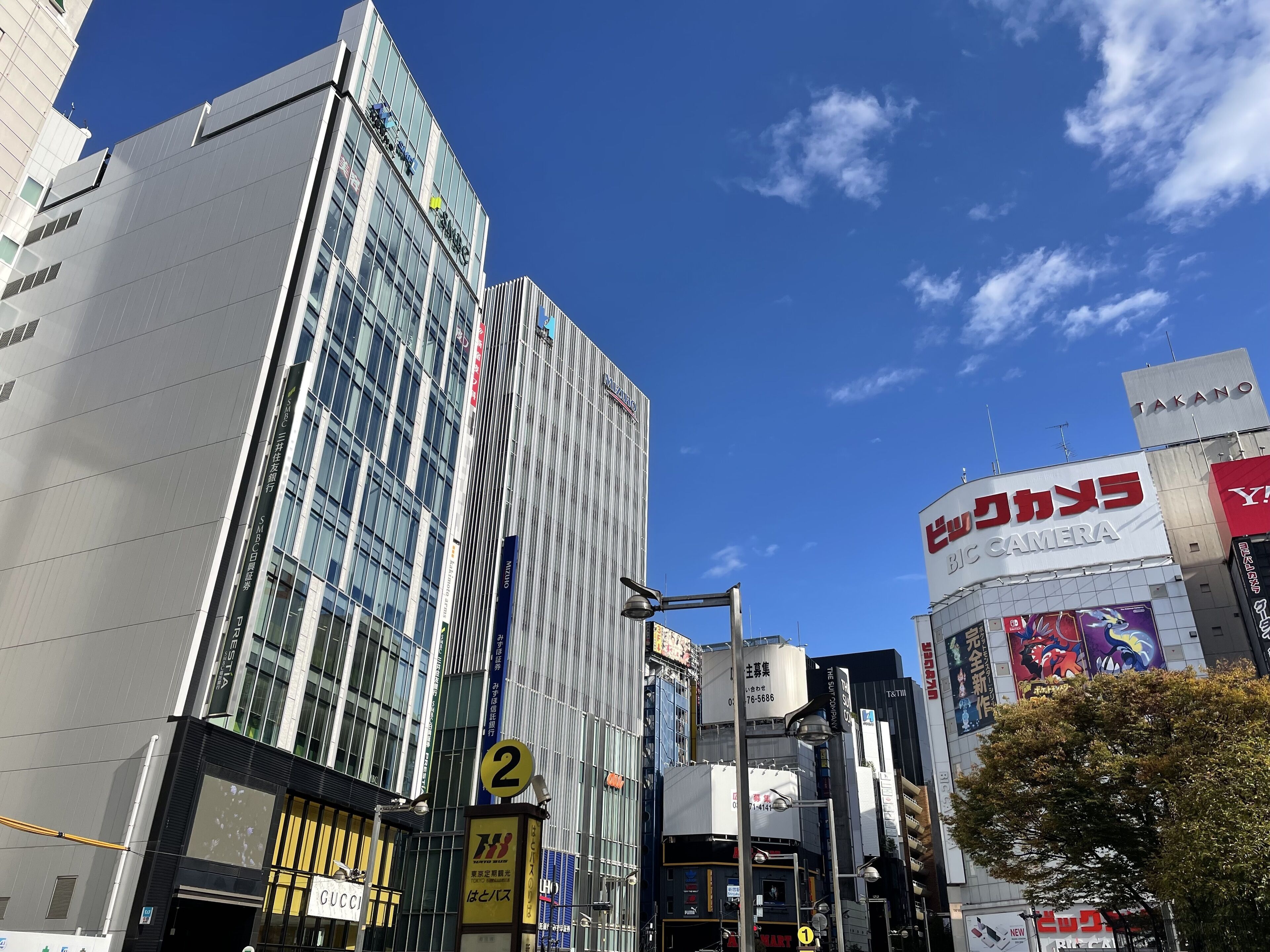 Paisagem urbana com edifícios modernos, incluindo um imponente arranha-céu de vidro e um edifício com a placa Takano.