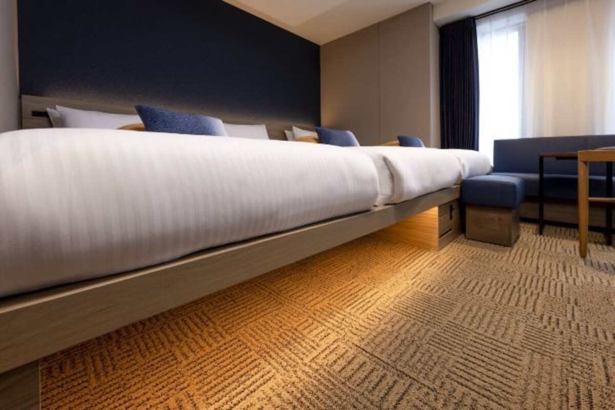 Een moderne hotelkamer met een bed, een bank en een klein tafeltje.