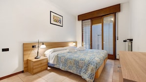 A bedroom with a bed, bedside table, lamp, and a window with a view. - Apartment 'Assenza 9' with Lake View, Wi-Fi and Air Conditioning (Brenzone sul Garda)