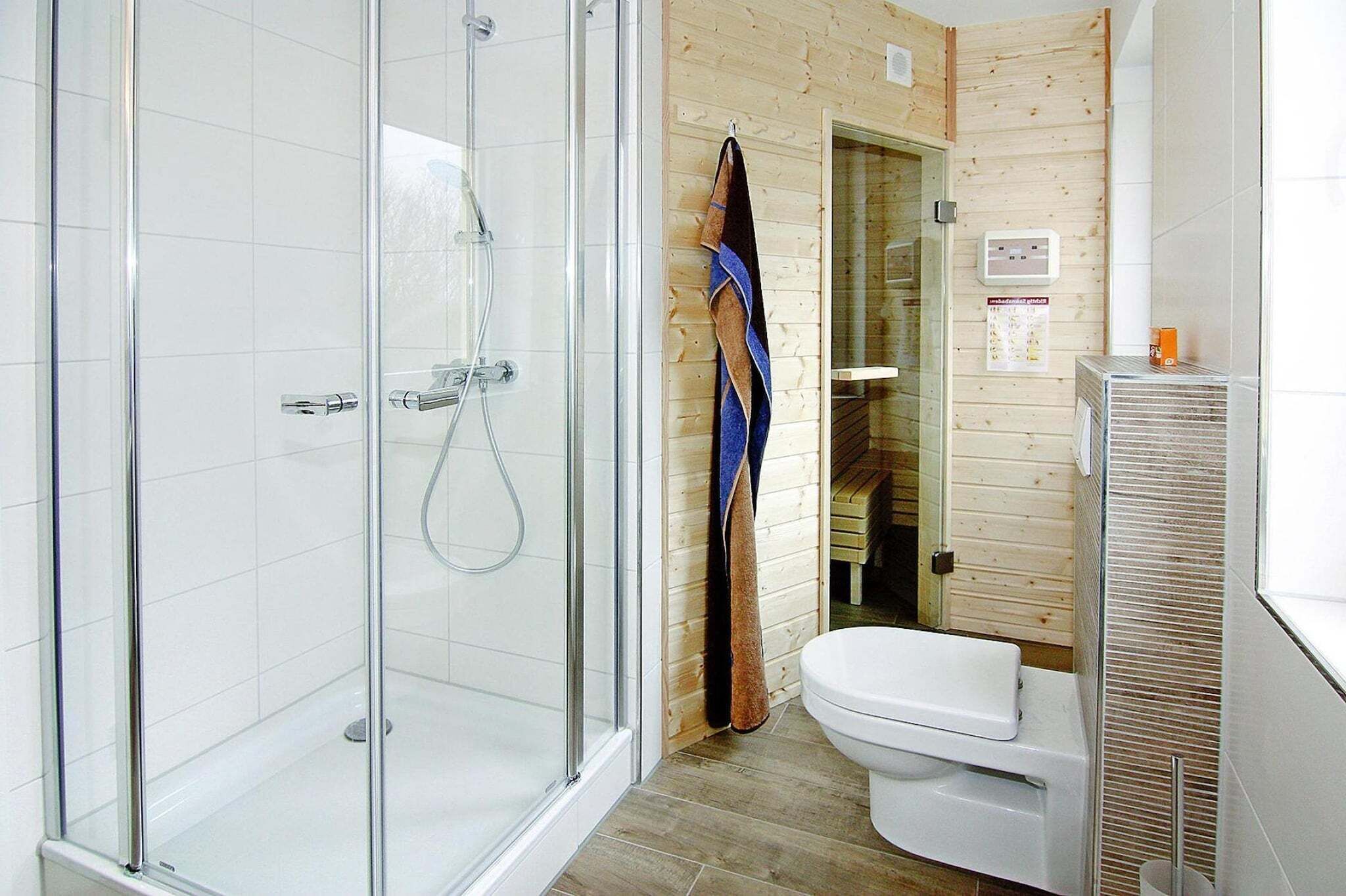 A modern bathroom with a glass-enclosed shower, a white toilet, and wooden paneling.
