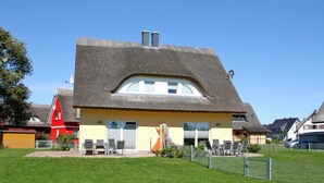 Ein Haus mit einem einzigartigen, gewölbten Dach und einem Anbau mit Strohdach.