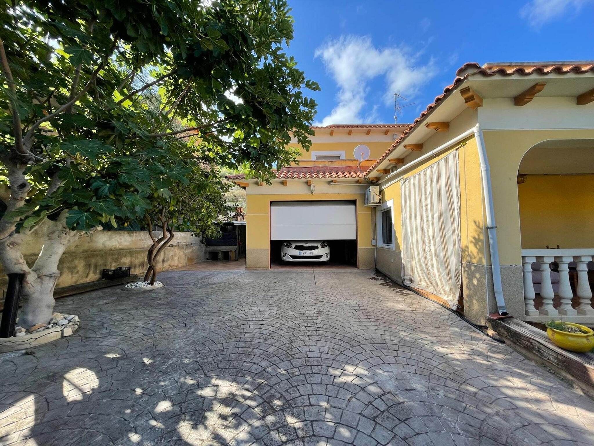 Un cortile lastricato con un garage, un albero e un edificio con tetto in tegole.