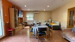 Uma sala de estar aconchegante com uma mesa de jantar, sofás e um armário.