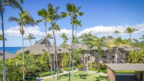 A resort with multiple buildings, palm trees, and a view of the ocean. - Aloha Condos, Kanaloa at Kona, Condo 2906, Oceanfront, AC (Kailua Kona)