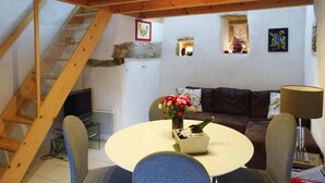 En hyggelig stue med en trætrap, et hvidt skab, en brun sofa og et rundt bord med en blomstervase og en flaske.