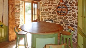 Un comedor rústico con pared de piedra, mesa de madera y sillas verdes.
