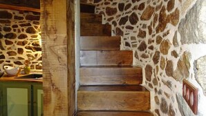Una escalera de madera junto a una pared de piedra.
