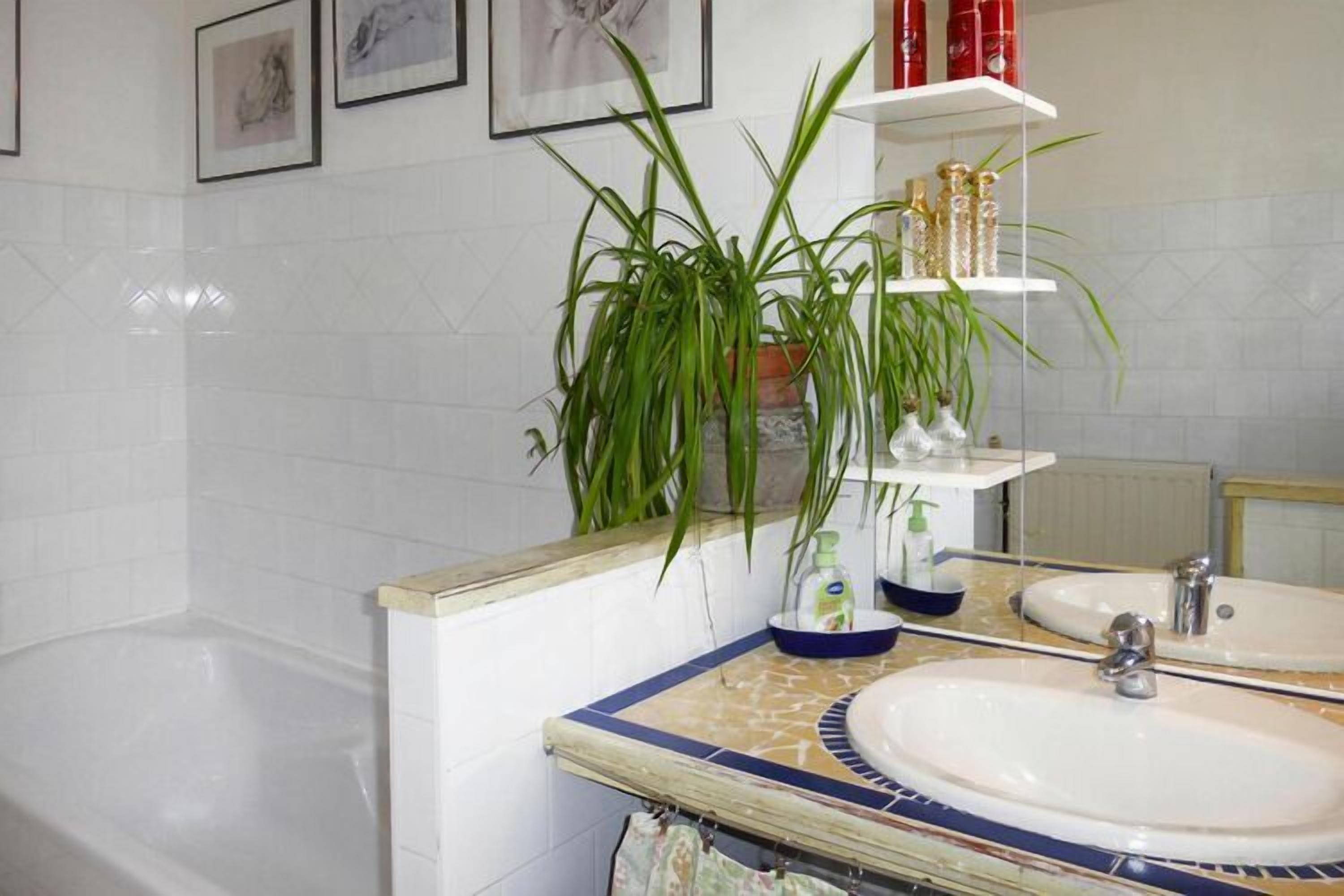 Un baño con dos lavamanos, una bañera, un espejo y un estante con artículos de aseo.