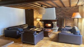 Ein gemütliches Wohnzimmer mit Kamin, Ledersofas und Holzbalkendecke.