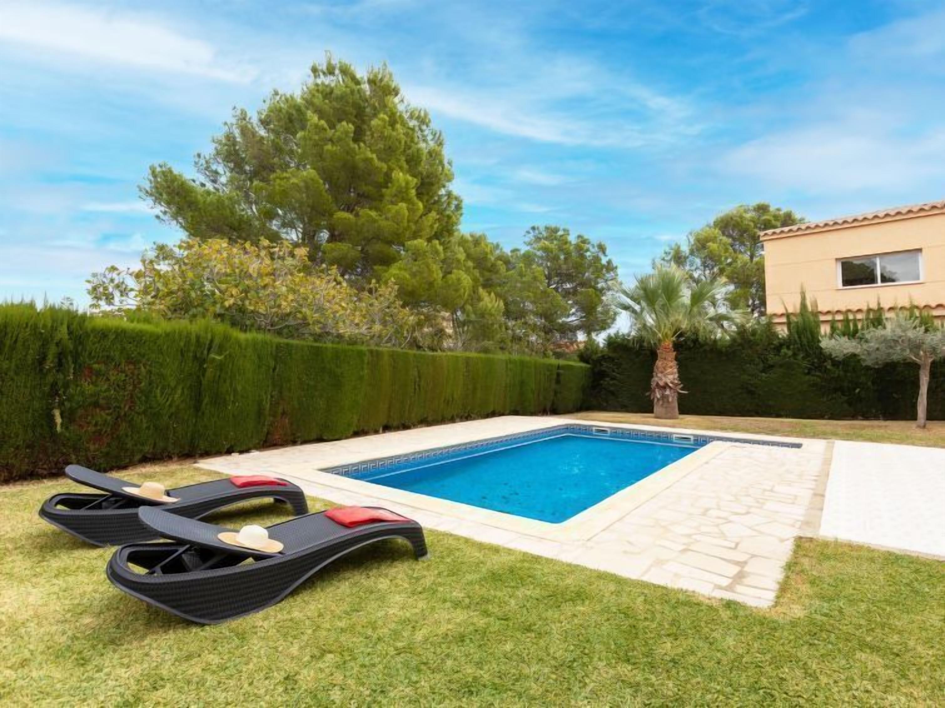 A swimming pool with lounge chairs and a well-maintained lawn.