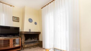 A living room with a television, fireplace, and a glass coffee table with pastries. - Villa Mar i Cel by Interhome (L'Ametlla de Mar)