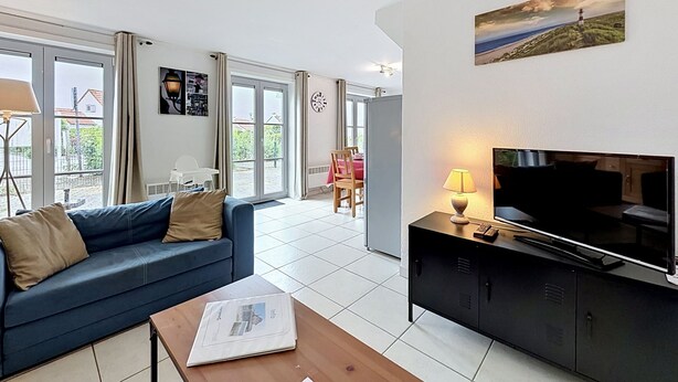 A modern living room with a sofa, a coffee table, a TV, and a painting on the wall. - Vissershuis 2 with parking by Interhome (De Haan)