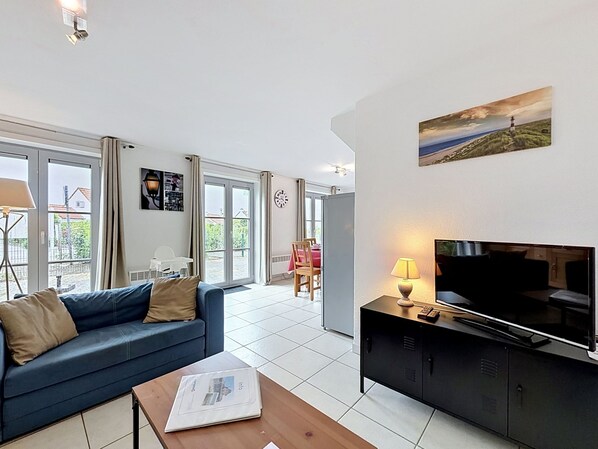 A modern living room with a sofa, a coffee table, a TV, and a painting on the wall.
