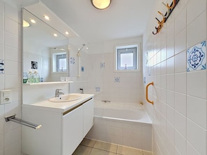 A modern bathroom with a sink, mirror, and bathtub.