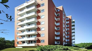 A multi-story residential building with balconies, a brick facade, and a clear blue sky. - Ferienwohnung, St. Peter-Ording (St. Peter-Ording)