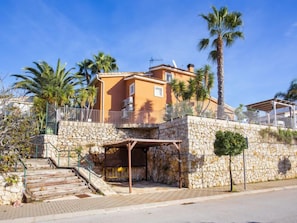 A two-story building with a stone facade, a balcony, and palm trees.