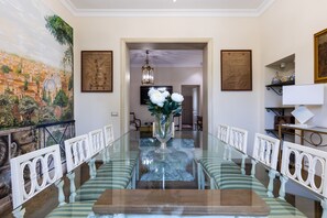 Une salle à manger avec une table à plateau en verre, des chaises à rayures et un vase rempli de fleurs.