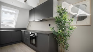 Eine moderne Küche mit dunklen Schränken, einem eingebauten Backofen und einem Blumentopf.