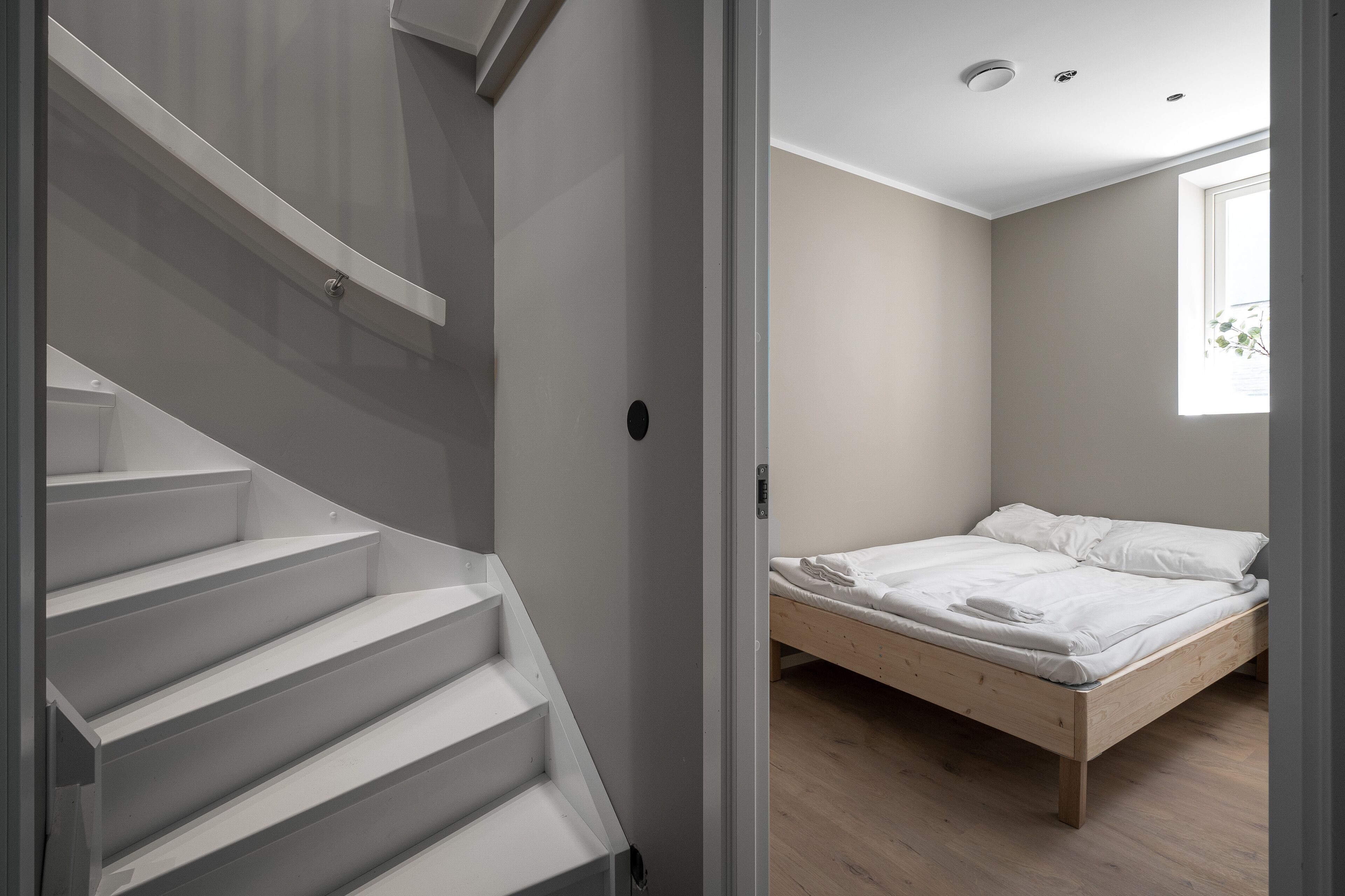 A bedroom with a wooden bed, a white mattress, and a wooden floor.