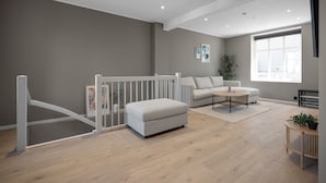 Ein modernes Wohnzimmer mit einem grauen Sofa, einem weißen Ottomanen und einem Couchtisch.
