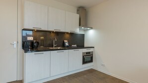 Een moderne keuken met witte kasten, een zwart aanrecht en een inbouwoven.