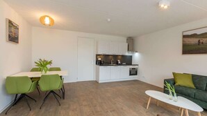 Een moderne, compacte leefruimte met een eethoek, kitchenette en een groene bank.
