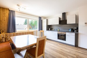 A modern kitchen with a dining area, wooden flooring, and a view of the outdoors. - Chalet in Fügen near Spieljochbahn (Fügen)