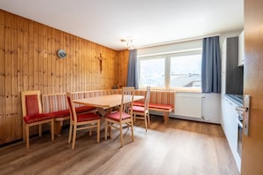 Un comedor con una mesa y sillas de madera, un reloj y un ventanal con vistas.