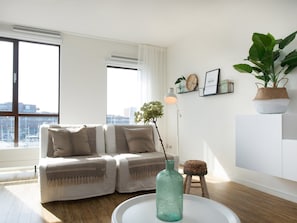 A modern living room with a sofa, a coffee table, a floor lamp, and a potted plant. - Apartment in Netherlands near the Beach (Den Haag)