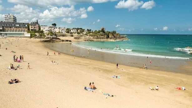 A beach with people sunbathing and swimming. There are buildings in the background. - House in Saint-Quay near 7 Beaches (St. Quay-Portrieux)