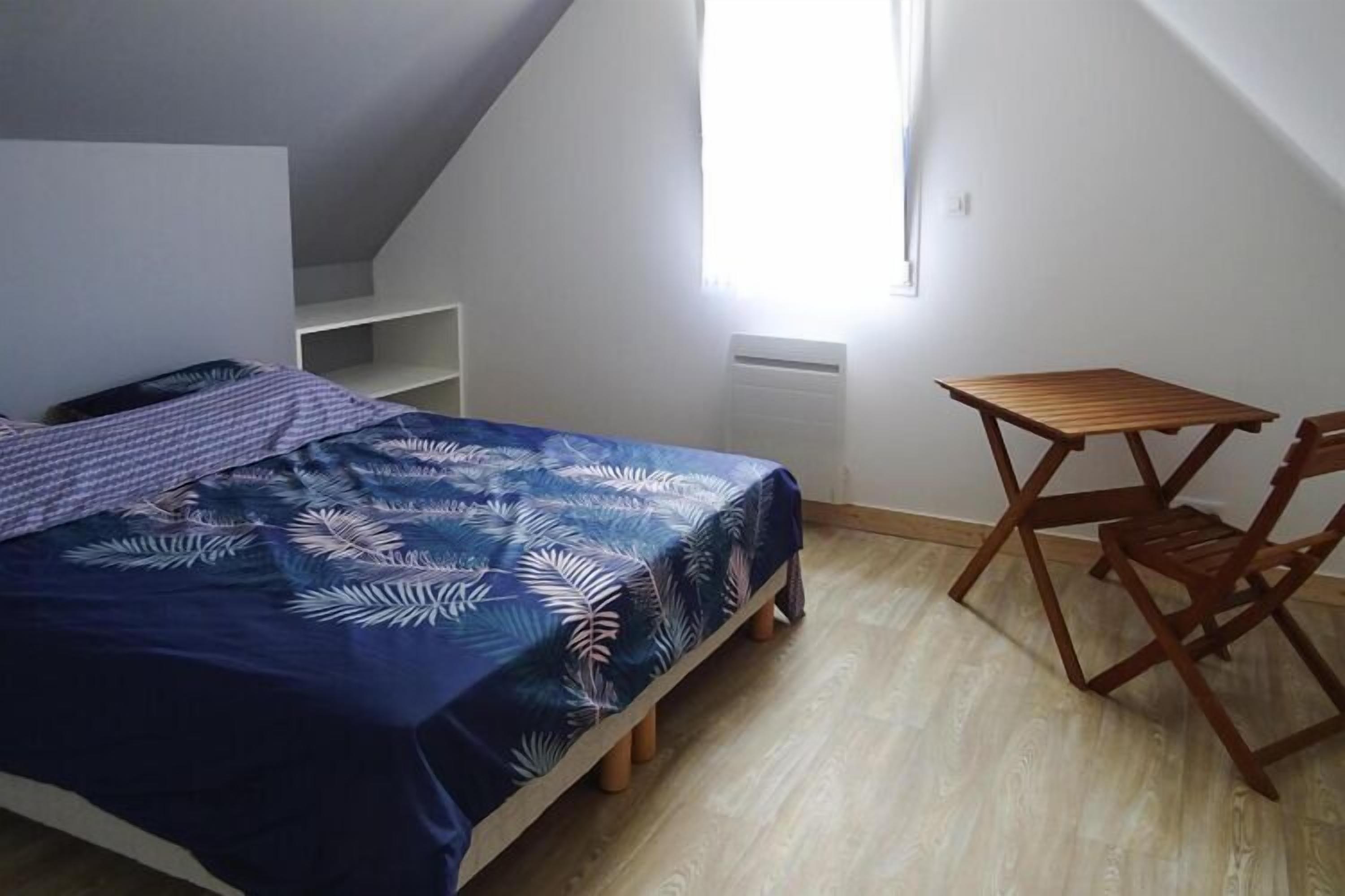 Un dormitorio con cama, una mesa de madera y una silla.