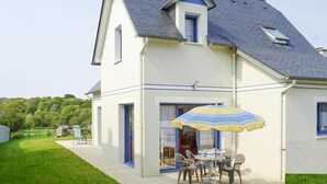 Una casa con patio amueblado, que incluye una mesa y sillas bajo un paraguas a rayas.
