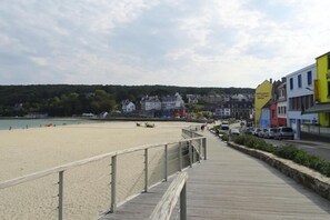 A beach with a wooden boardwalk, buildings, and a restaurant sign.