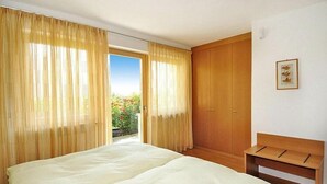 Um quarto com uma cama, um guarda-roupa de madeira e um banco.