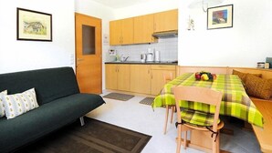 Um espaço de estar compacto com cozinha compacta, um sofá, uma mesa de jantar com toalha quadriculada e um pequeno espaço para refeições.