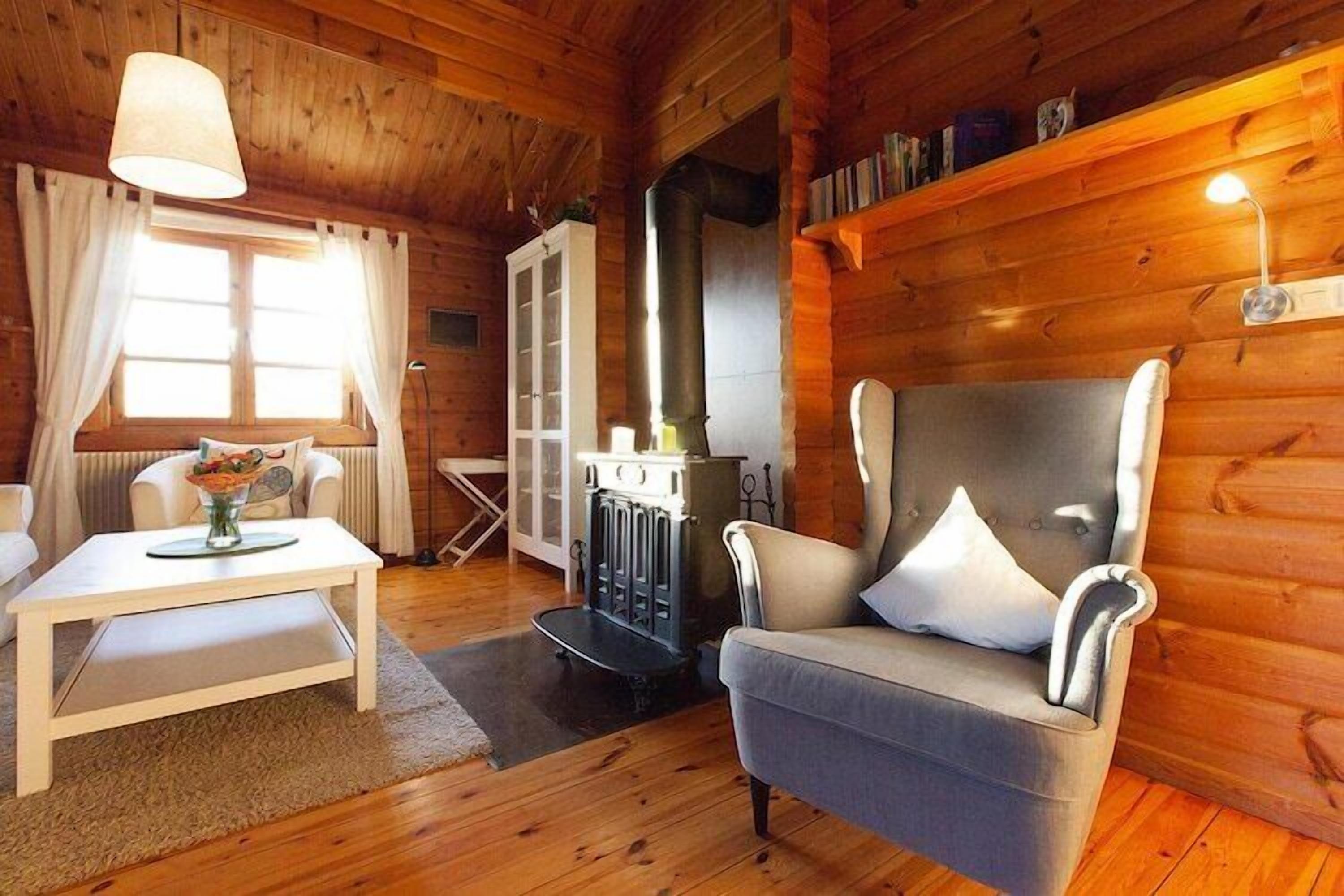 Ein gemütliches Holzhaus-Interieur mit einer Couch, einem Tisch mit einer Vase, einem Kamin und Holzwänden.
