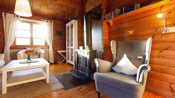 Ein gemütliches Holzhaus-Interieur mit einer Couch, einem Tisch mit einer Vase, einem Kamin und Holzwänden.