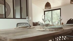 Een eetgedeelte met een houten tafel gedekt voor vier personen, omringd door zwarte stoelen.