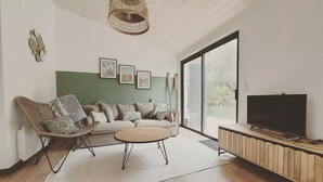 Een moderne woonkamer met een bank, een salontafel, een televisie en een groot raam.