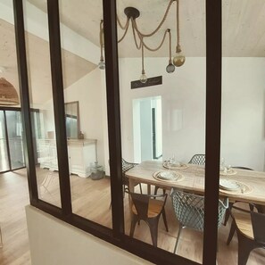 A dining area with a wooden table set for four, surrounded by chairs.