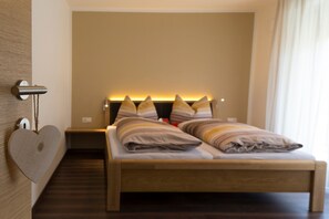 Une chambre moderne avec un lit en bois, une décoration en forme de cœur sur le mur et une table de chevet avec une lampe.