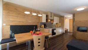 Eine moderne Küche mit Holdekor, ein Essbereich mit einer Bank und ein Fernseher im Wohnbereich.