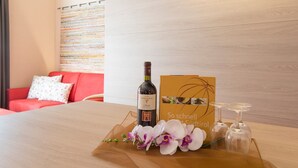 Une chambre d’hôtel avec une table en bois, une bouteille de vin Merlot, une carte et des verres à vin.