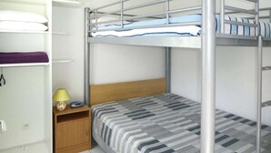A bunk bed with a wooden headboard, a bedside table with a lamp, and a shelf with pillows. - Terraced holiday home in Moliets (Moliets)