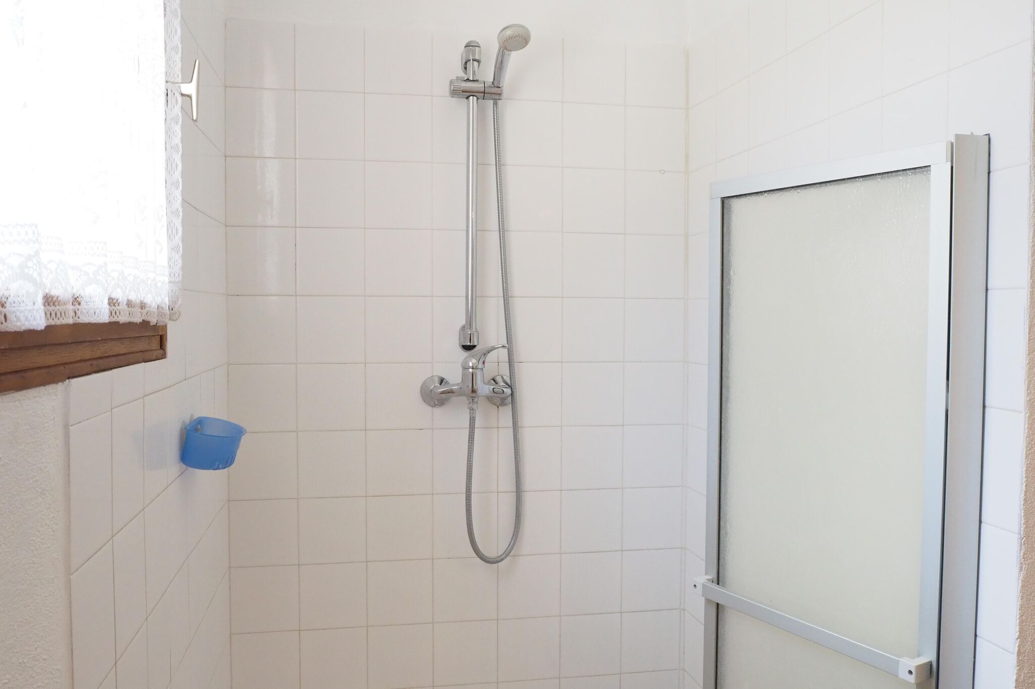A shower with a handheld showerhead and a wall-mounted faucet.
