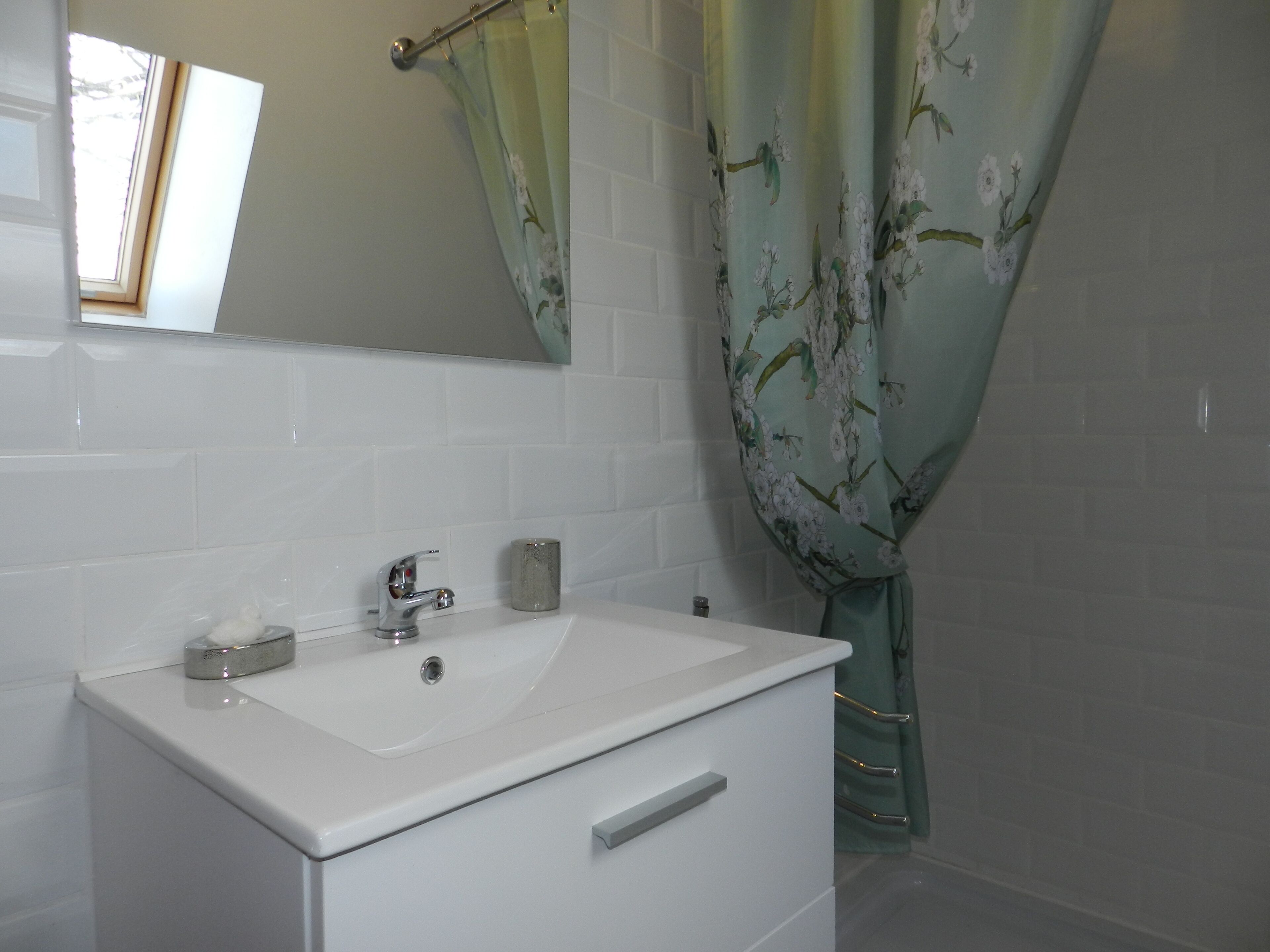 A bathroom with a white sink, a mirror, and a shower curtain with a floral pattern.