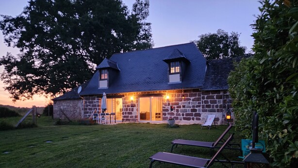 A stone house with a sloped roof, a front porch, and a lawn. - Quiet cottage in the countryside. (Segonzac)