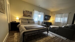 A bedroom with a bed, a sofa, a TV, and a desk.